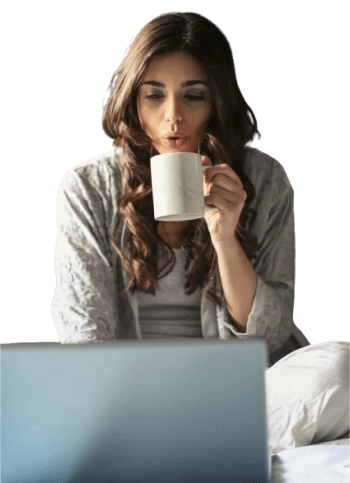 A girl in front of a laptop with a cup of coffee in her hand